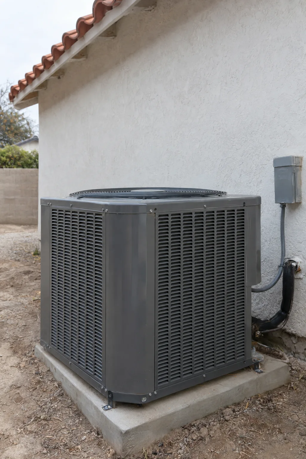 A new central air conditioning condenser unit installed on a concrete pad beside a stucco wall in a Los Angeles side yard, photographed in bright midday sunlight